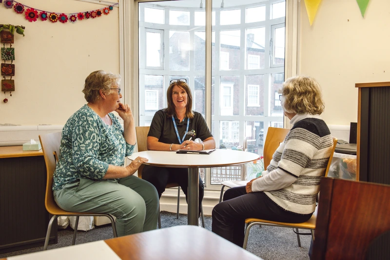 three woman sat at a round table talking
